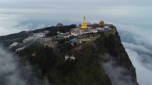 Time lapse of golden buddha statue at  Jinding Emei mountain Sichuan China  with sea of clouds flowing by the cliff UNESCO World Heritage site time-lapse aerial footage