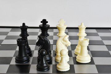 Black and white chess pieces on a chessboard close-up on a white background. Checkmate. Queen, king, pawn