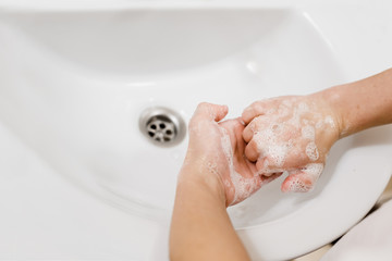 Child cleaning hands in bathroom to prevent germs and bacteria