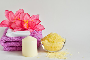 Spa setting with a candle, a towel, bath salt and a pink flower, incense sticks on a white background, Place for text