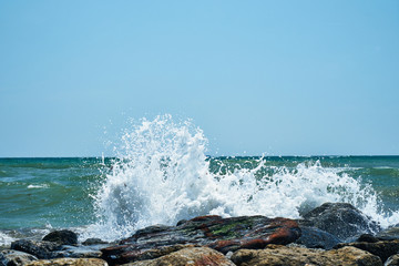 Image of the sea shore. The wave breaks on the stones.