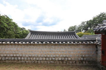 Obraz premium Traditional Korean house roof behind the stone wall. Dosanseowon, Andong, Gyeongsangbuk-do