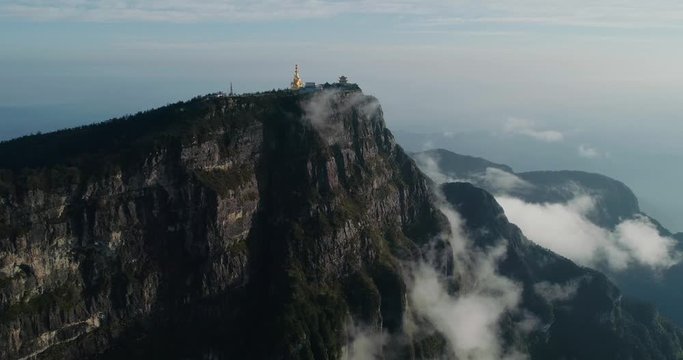 Aerial view of golden buddha statue and Chinese Traditional Architecture at Jinding Emei mountain summit by the edge of cliff clouds floating  UNESCO World Heritage site 4k drone footage