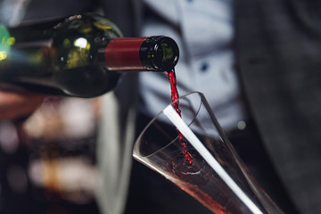 Sommelier pouring red wine into carafe decanter to make aeration drink
