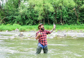 Fishing requires you to be mindful and fully present in moment. Fishing masculine hobby. Brutal man wear rubber boots stand in river water. Weekend activity. Fisher fishing equipment. Fish on hook