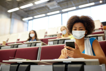 education, healthcare and pandemic concept - african student girl wearing face protective medical...