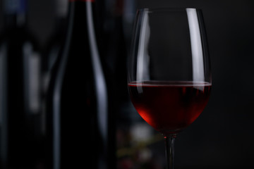 The red wine in the glass, along with a bottle of wine made from red grapes, is laid on a wooden floor and a beautiful backdrop. Ready for partying