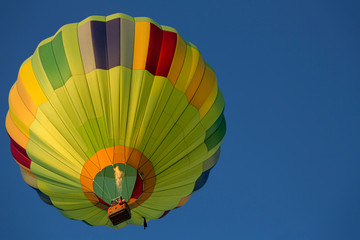 Isolated skyward view of a colorful hot air balloon against clear blue sky
