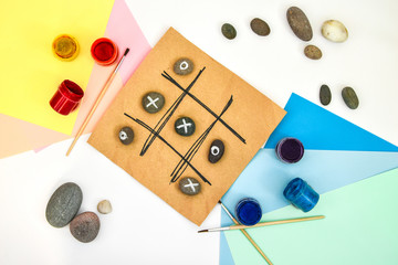top view of tic tac toe game with stones marked with naughts and crosses. Children's art project, a...