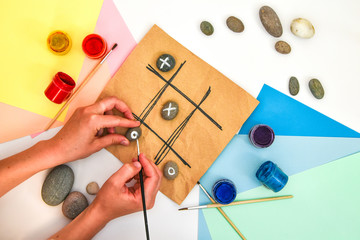 top view of tic tac toe game with stones marked with naughts and crosses. Children's art project, a...