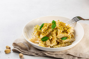 Sicilian  ricotta cheese and pistachio pasta, with zucchini and basil leaves. White background, copy space.