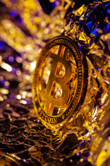 Gold Bitcoin on the reflect surface with golden an blue neon light. Macro shot of popular cruptocurrency, Halving of BTC