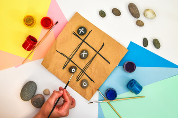 top view of tic tac toe game with stones marked with naughts and crosses. Children's art project, a...