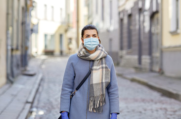 health, safety and pandemic concept - young woman wearing protective medical mask on empty city street