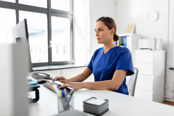 medicine, technology and healthcare concept - female doctor or nurse with computer working at hospital