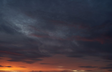 A beautiful evening blue sky at sunset with flaming bright light clouds. Warm evening.