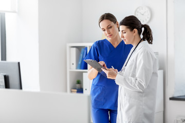 medicine, healthcare and people concept - doctor and nurse with clipboard at hospital