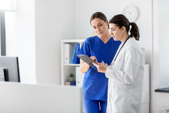 medicine, healthcare and people concept - doctor and nurse with clipboard at hospital