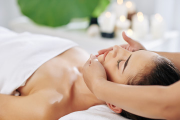 Obraz na płótnie Canvas Young woman enjoying facial beauty treatment in spa salon and getting lifting massage