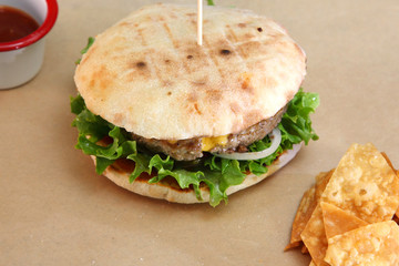 Burger with meat and vegetables. Double cheese burger. Hot burger in a burning sauce. 