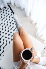 Top view image of a beautiful woman drinking hot coffee in bedroom at home in the morning
