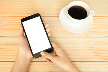 hand of women holding smartphone and hot cooffee on wooden table