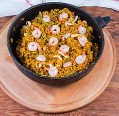 Cooked seafood paella in pan on wooden serving board