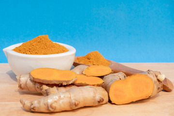 turmeric fresh and turmeric powder on blue background. concept healthy spice diet