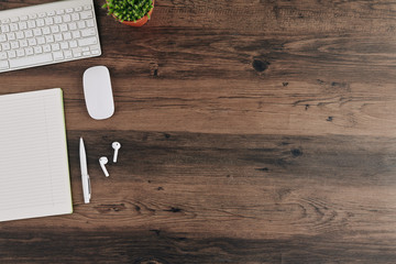 Wooden table with opened textbook, keyboard and wireless earbuds: education background