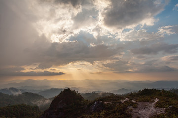 Sun rays through the cloudy sky and mountains. Wallpaper and background concept.