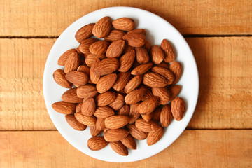 Almonds nuts on white plate on wooden background ,  view on - Roasted almond for snack