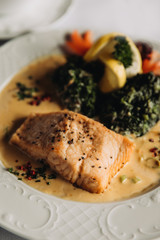 Slice of red fried fish on a white plate with vegetables