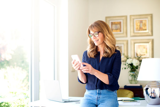 Happy woman text messaging while working from home