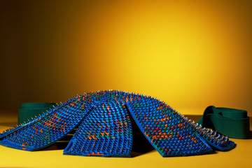A blue massage mat shaped like chamomile lies on a yellow background. Advertising, thematic and subject shooting. For relaxation and health.