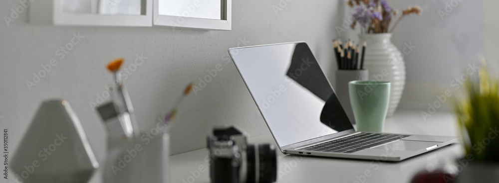 Wall mural side view of designer office desk with laptop, painting tools, camera and decorations