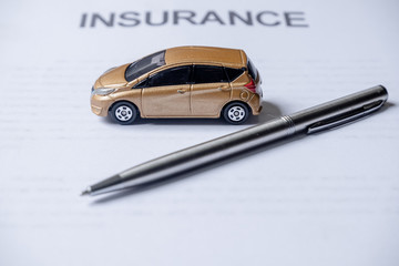 Car and pen on insurance documents. Car insurance concept
