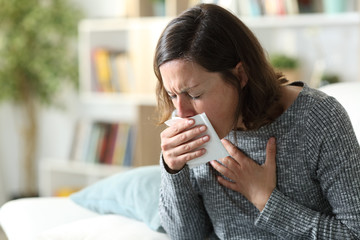 Sick adult woman coughing covering mouth with tissue at home - obrazy, fototapety, plakaty