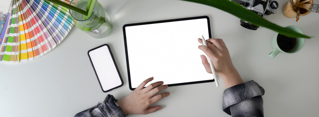 Overhead shot of female freelancer working with blank screen tablet and smartphone