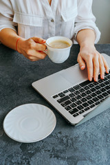 girl typing on a laptop keyboard, next is a mug of coffee