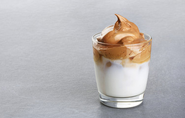 Glass with dalgona coffee on a gray background. Ice milk and foamy whipped coffee.