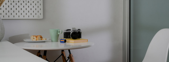Cropped shot of coffee table with coffee mug, camera, bread and copy space