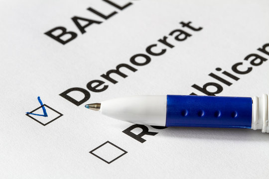 Checklist concept. Closeup of ballot paper with words Democrat and Republican and a pen on it. A checkmark for Democrat in the checkbox.