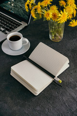 girl works at a laptop, next is a coffee mug and a diary on a black background