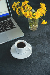 Obraz na płótnie Canvas girl works at a laptop, next is a coffee mug and a diary on a black background