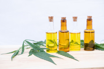Glass bottle with extracting CBD oil formula and hemp leaf on a wooden floor. Medical cannabis concept