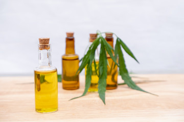 Glass bottle with extracting CBD oil formula and hemp leaf on a wooden floor. Medical cannabis concept