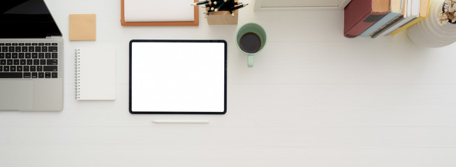 Minimal worktable with mock-up tablet, coffee mug, notebooks, stationery and copy space on white desk