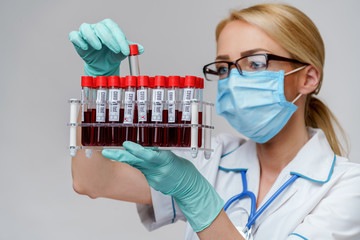 medical doctor nurse woman wearing protective mask and gloves - holding rack with virus blood tests