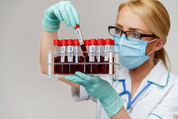 medical doctor nurse woman wearing protective mask and gloves - holding rack with virus blood tests