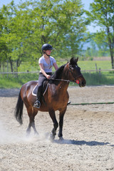 Girl is riding sorrel horse in the riding school